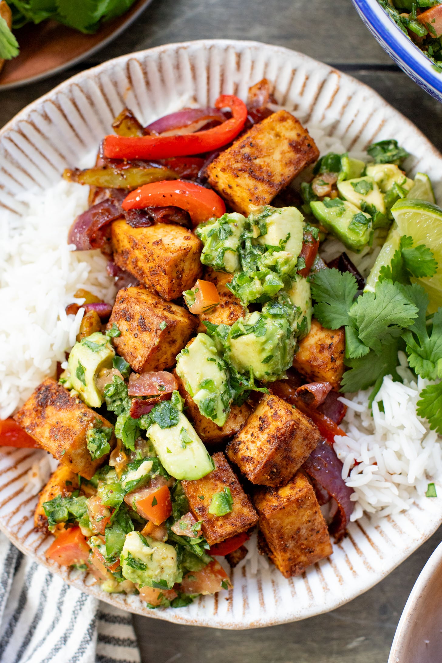 These Tofu Fajita Rice Bowls are a quick sheet pan dinner recipe! Packed with protein & veggies, and topped with avocado salsa | ThisSavoryVegan.com