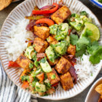 These Tofu Fajita Rice Bowls are a quick sheet pan dinner recipe! Packed with protein & veggies, and topped with avocado salsa | ThisSavoryVegan.com