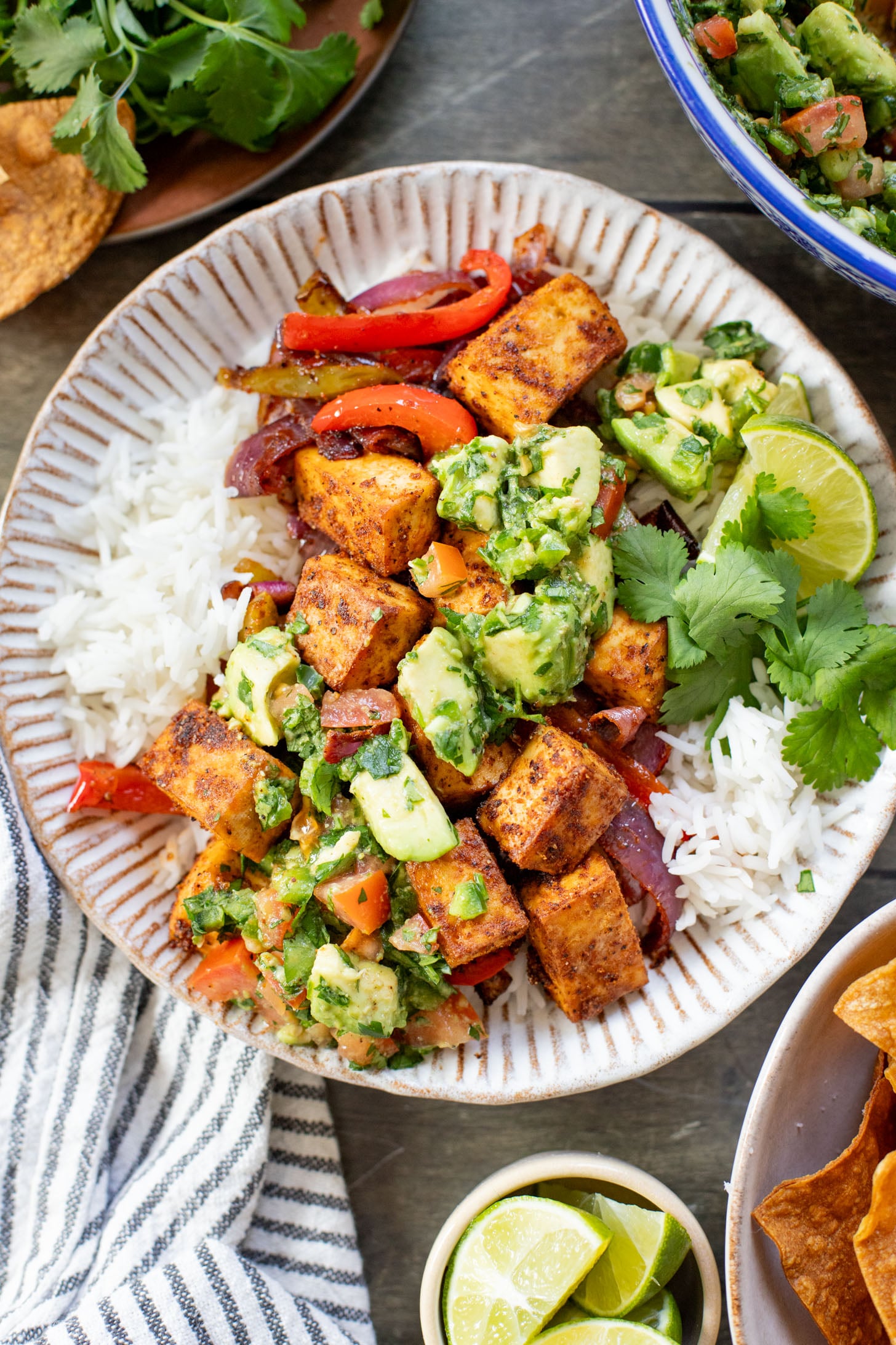 These Tofu Fajita Rice Bowls are a quick sheet pan dinner recipe! Packed with protein & veggies, and topped with avocado salsa | ThisSavoryVegan.com