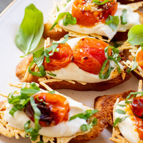 These Roasted Tomato & Ricotta Crostini are the best dairy-free appetizer! Bread slices are topped with vegan parm, tofu ricotta & burst tomatoes | ThisSavoryVegan.com