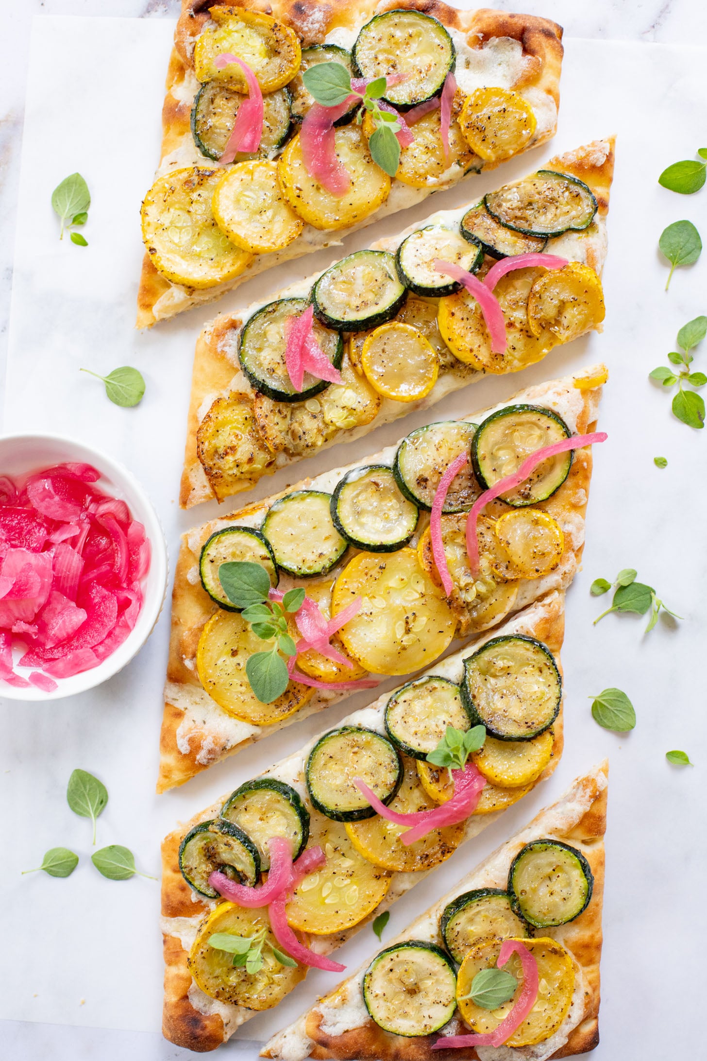 A yummy summer appetizer or quick dinner - this Cheesy Zucchini Flatbread is made with dairy-free cheese and zucchini slices | ThisSavoryVegan.com