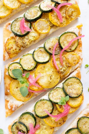 A yummy summer appetizer or quick dinner - this Cheesy Zucchini Flatbread is made with dairy-free cheese and zucchini slices | ThisSavoryVegan.com