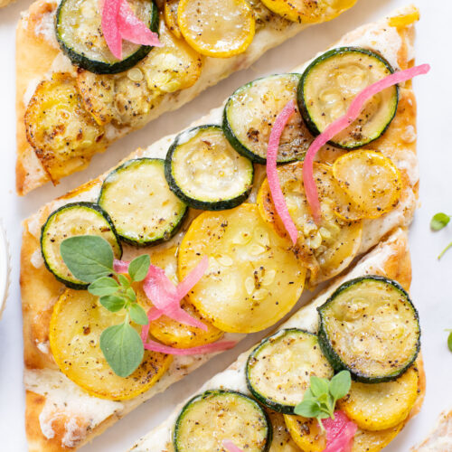 A yummy summer appetizer or quick dinner - this Cheesy Zucchini Flatbread is made with dairy-free cheese and zucchini slices | ThisSavoryVegan.com