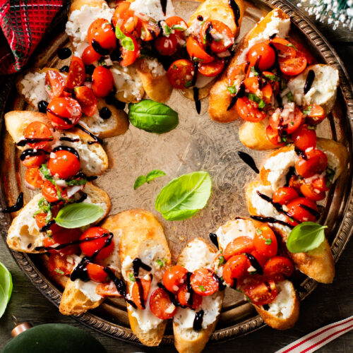This Christmas Bruschetta Wreath is a holiday party must make appetizer! Made with dairy-free cheese spread, marinated tomatoes & balsamic glaze | ThisSavoryVegan.com