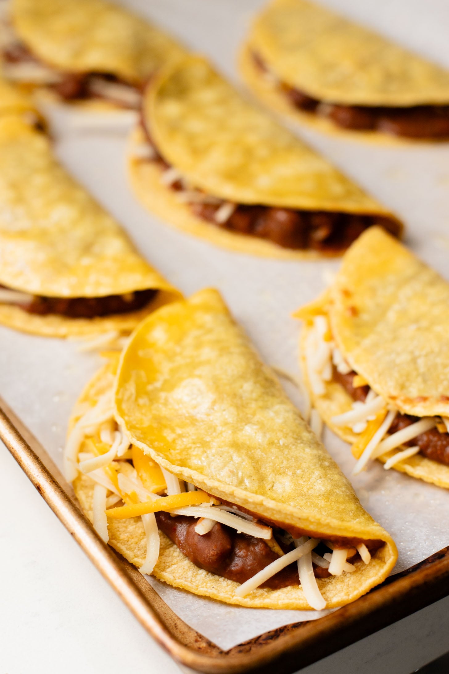 These Cheesy Bean Tacos are the perfect family weeknight dinner. Tortillas are stuffed with dairy-free cheese & beans and baked until crispy | ThisSavoryVegan.com