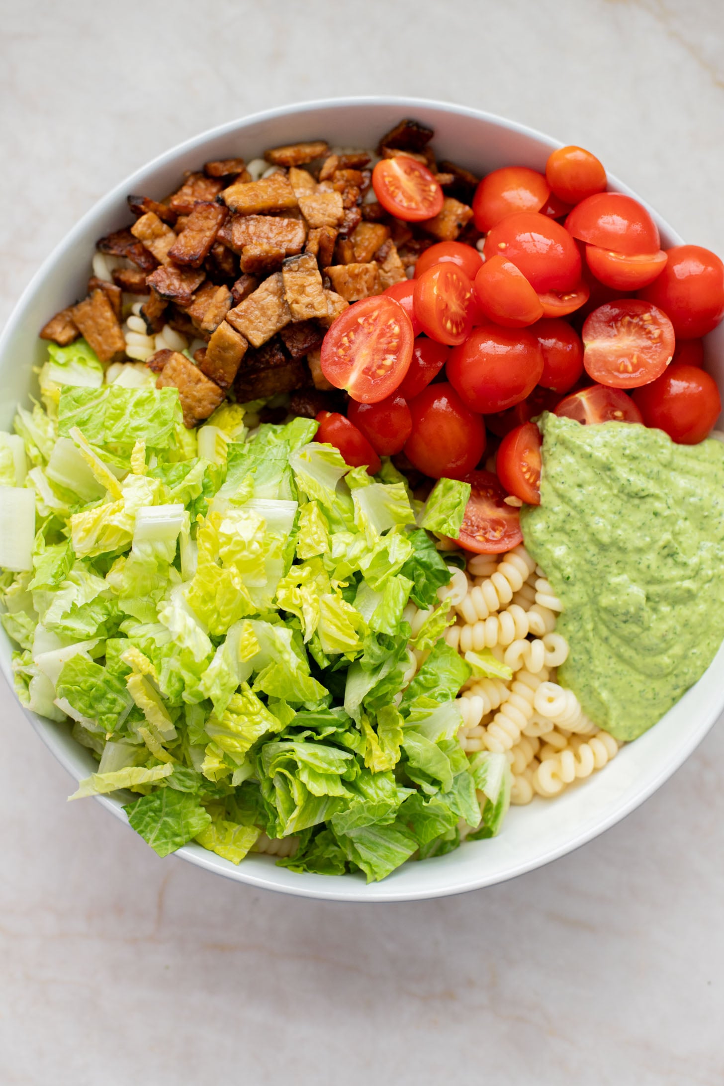 This TTLA Pasta Salad is the ultimate vegan take on a BLT pasta salad. It has a creamy avocado dressing, crispy tempeh and fresh veggies | ThisSavoryVegan.com