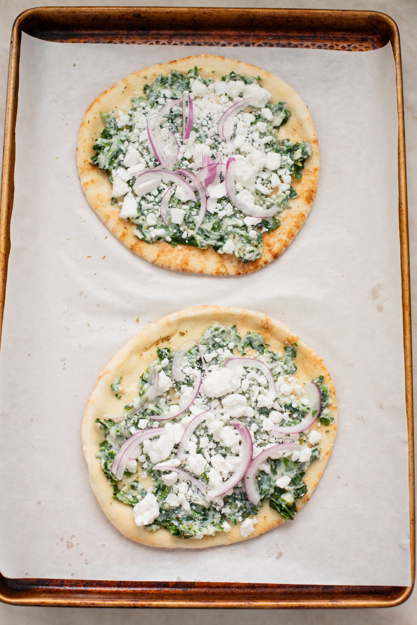 These Spinach & Feta Pita Pizzas are the perfect quick vegan dinner. Made with just a few ingredients and ready in less than 30 minutes. Kid-friendly too | ThisSavoryVegan.com