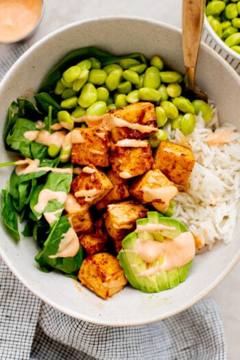These Sweet Chili Tofu Bowls are loaded with crispy tofu, edamame, rice, avocado, greens & a spicy vegan mayo | ThisSavoryVegan.com