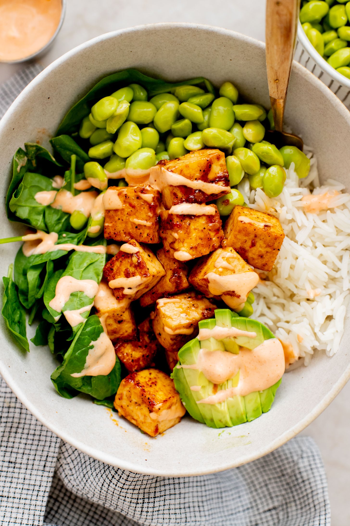 These Sweet Chili Tofu Bowls are loaded with crispy tofu, edamame, rice, avocado, greens & a spicy vegan mayo | ThisSavoryVegan.com